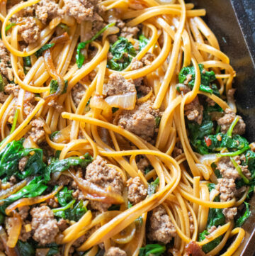 linguine with beef and spinach in a cast iron skillet.