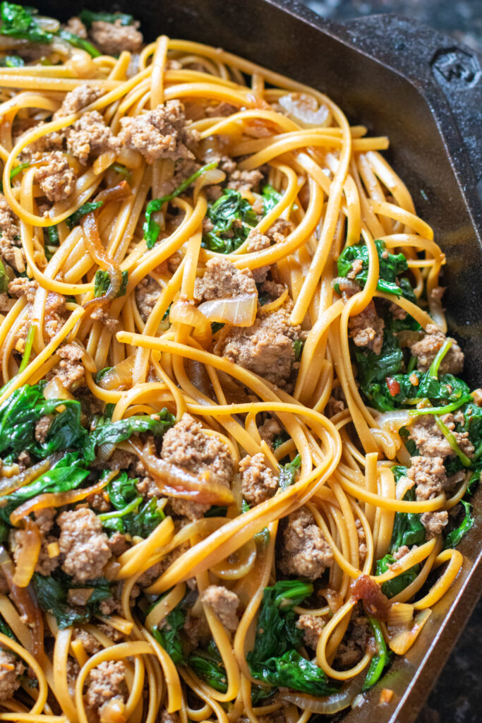 linguine with beef. spinach, and onions in a cast iron skillet 