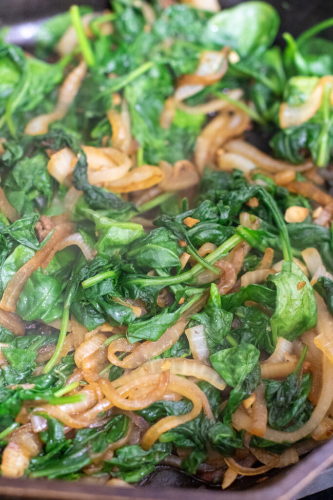 sauteed onions and spinach in a cast iron 