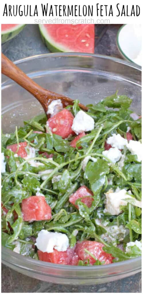 arugula watermelon feta salad in a large bowl with a wooden spoon with Pinterest pin text.