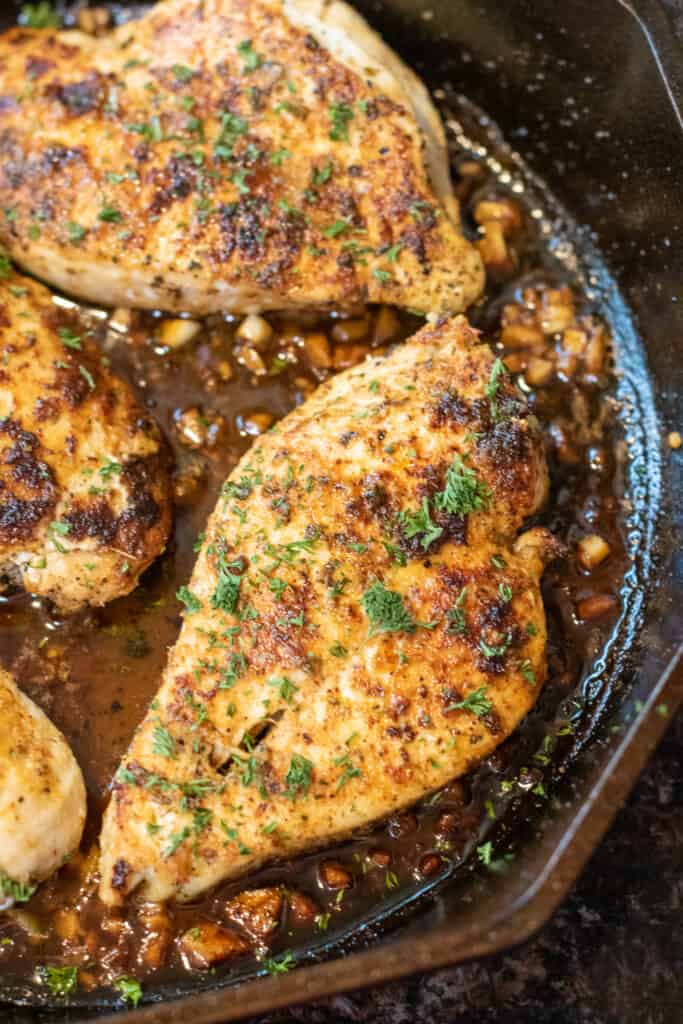 cooked garlic butter chicken in a pan with fresh parsley