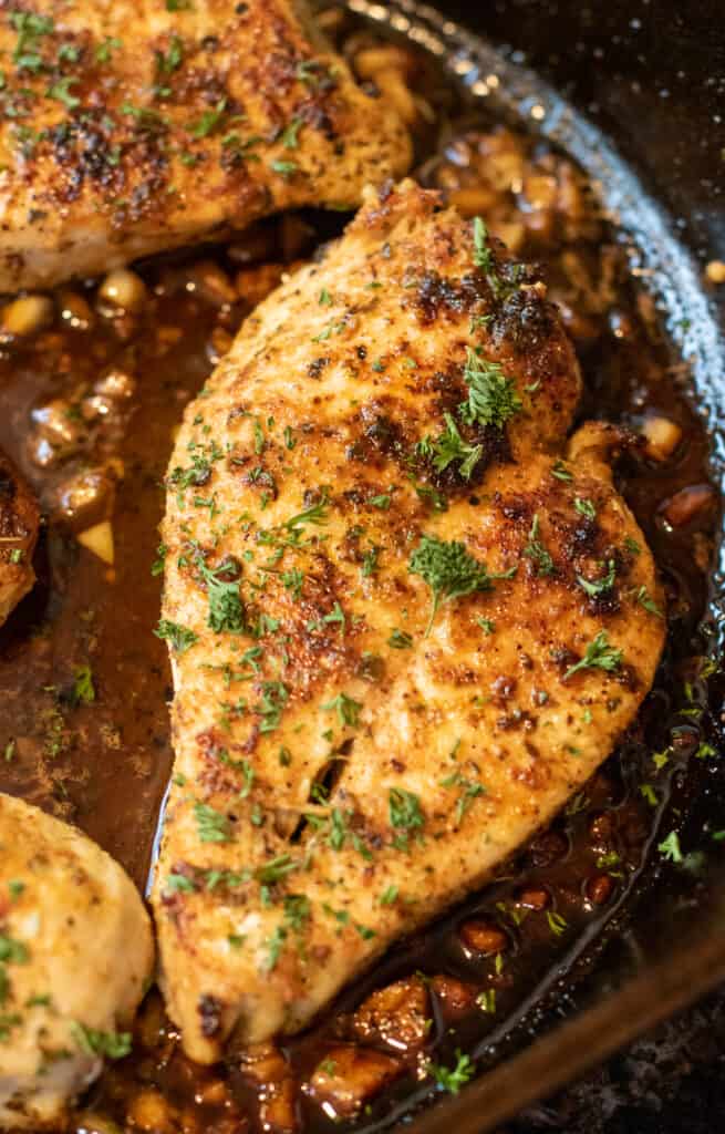 cooked garlic butter chicken in a pan with fresh parsley.