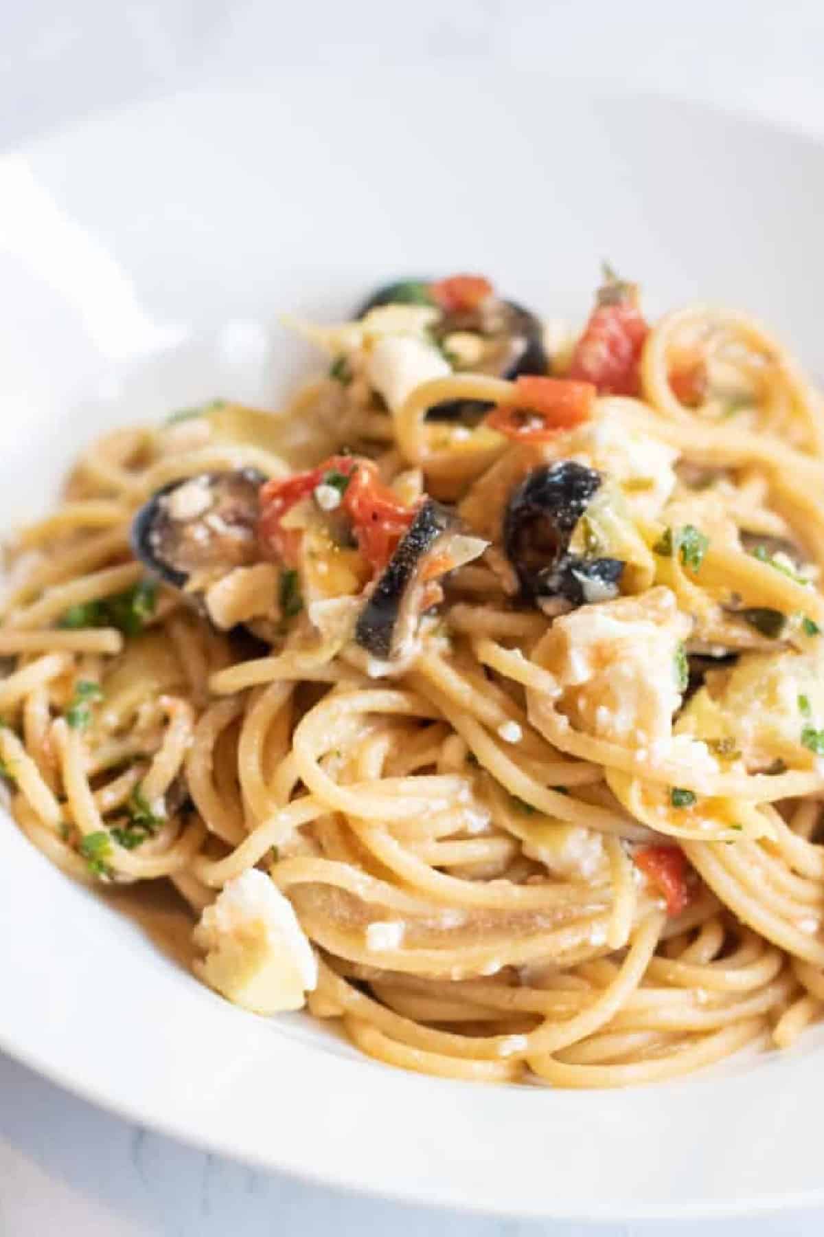 greek pasta with olive and tomatoes and feta cheesein a bowl.