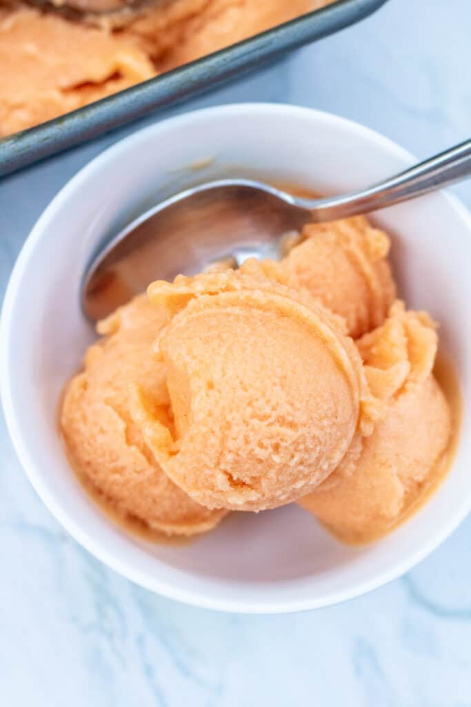 a bowl of peach sorbet with a spoon.