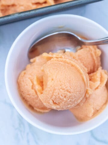 a bowl of peach sorbet with a spoon.