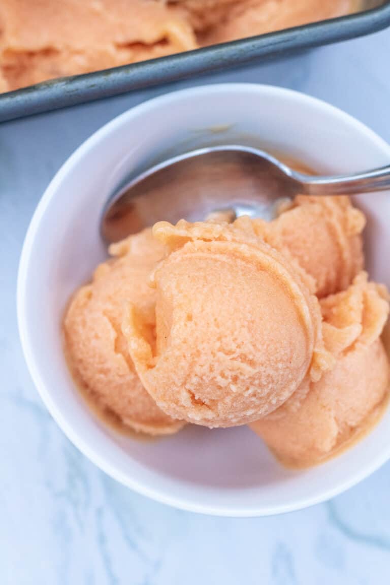 a bowl of peach sorbet with a spoon.
