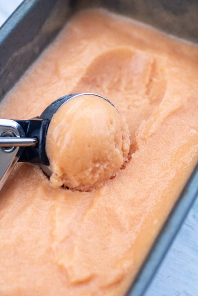peach sorbet being scooped with an ice cream scoop