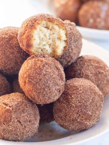 bowl of cinnamon sugar munchkins .with glazed munchkins in a bowl behind.