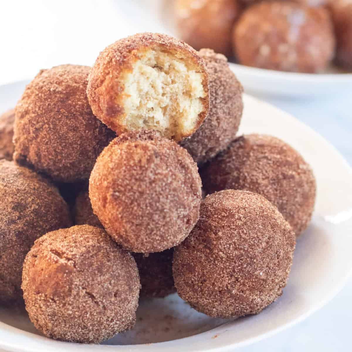 bowl of cinnamon sugar munchkins .with glazed munchkins in a bowl behind.