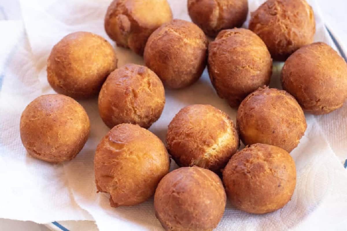 fresh fried donut holes on a paper towel plate.