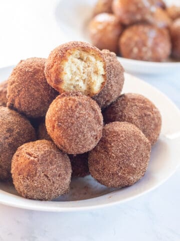 bowl of cinnamon sugar munchkins .with glazed munchkins in a bowl behind