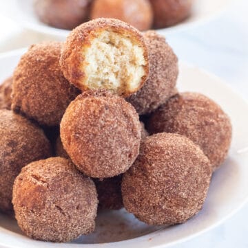 bowl of cinnamon sugar munchkins with glazed munchkins in a bowl behind.