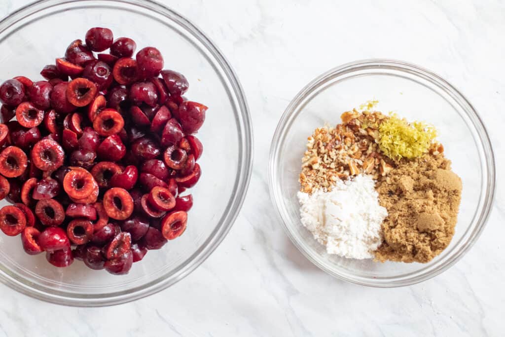 a bowl of pitted cherries and a bowl with flour, sugar, pecans, and lemon zest