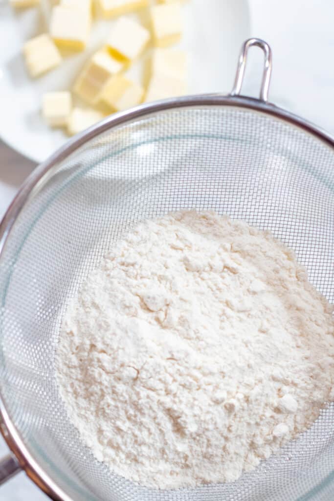 flour sifting into bowl and cubed butter