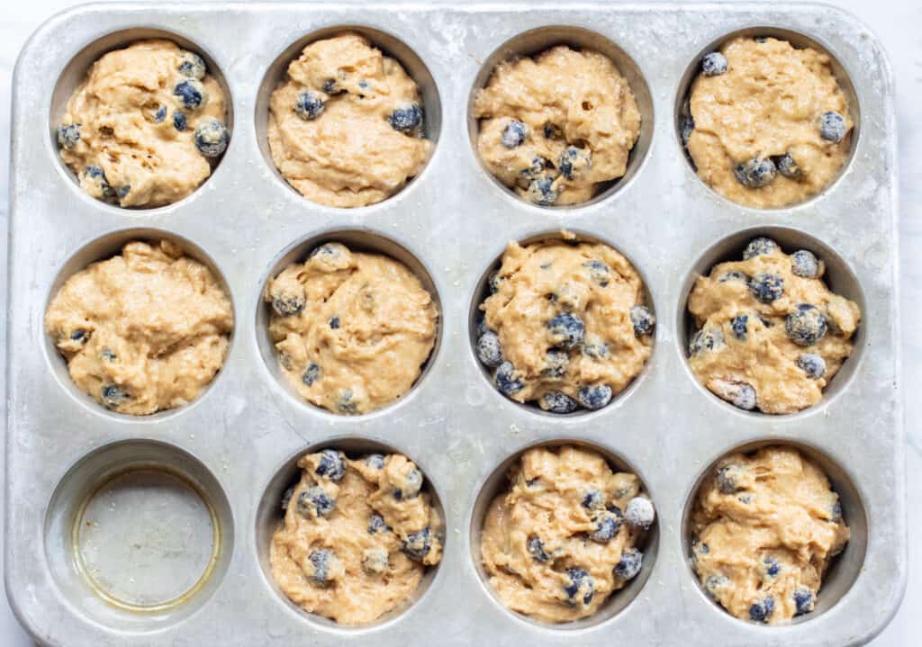 muffin tin filled with blueberry muffin dough