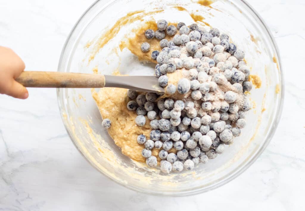 blueberries being folded into a muffin dough 
