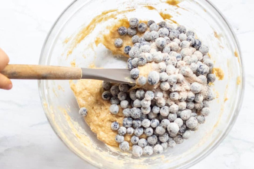 blueberries being folded into a muffin dough.