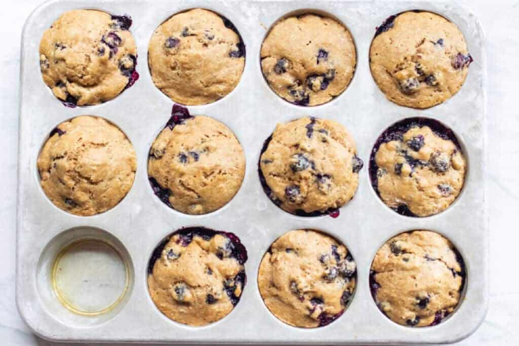 a muffin tin with baked blueberry muffins.