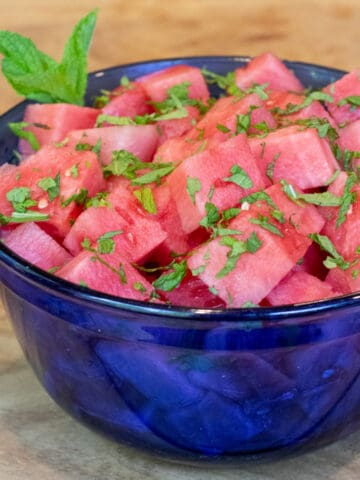 a blue bowl of cubed vodka with mint.