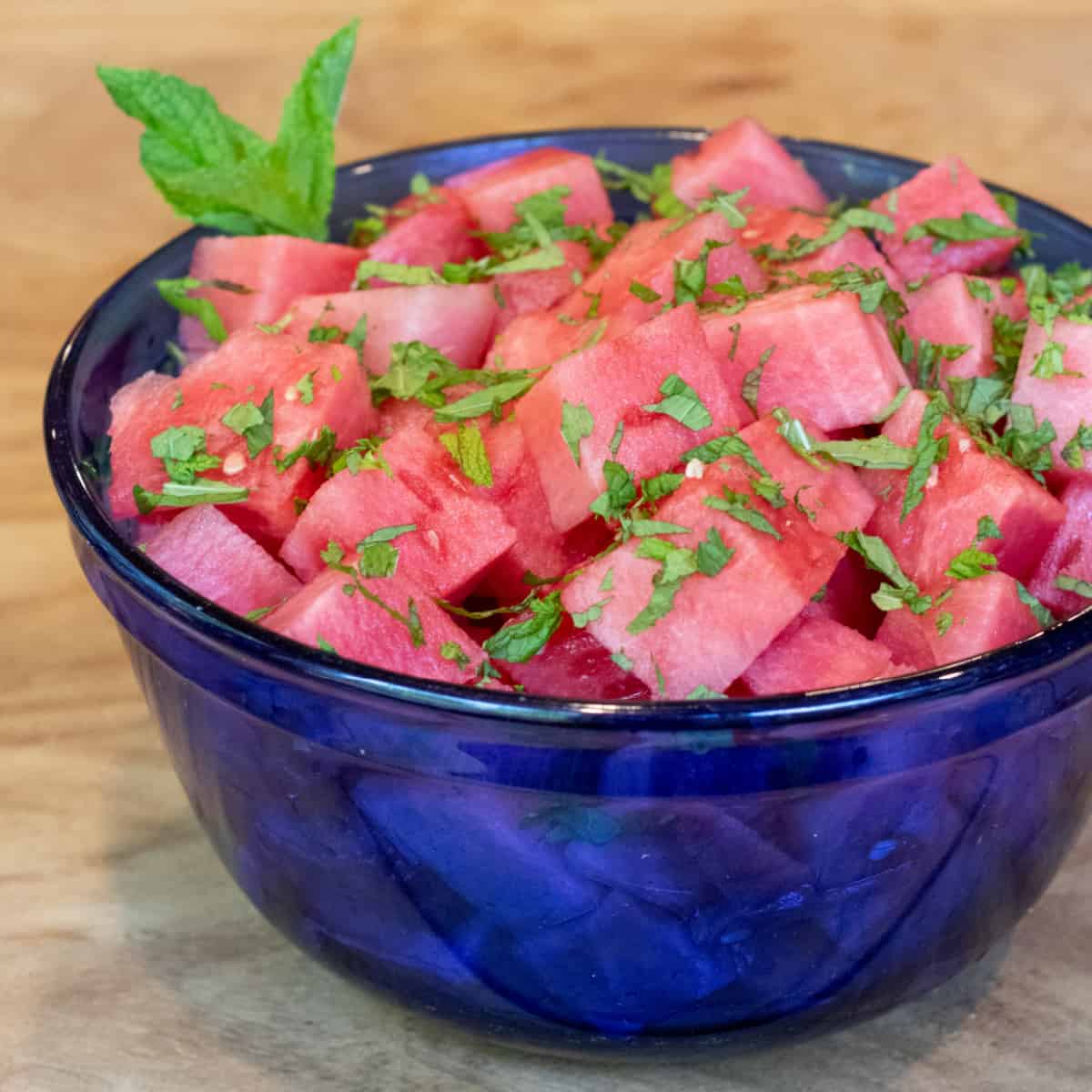 a blue bowl of cubed vodka with mint.