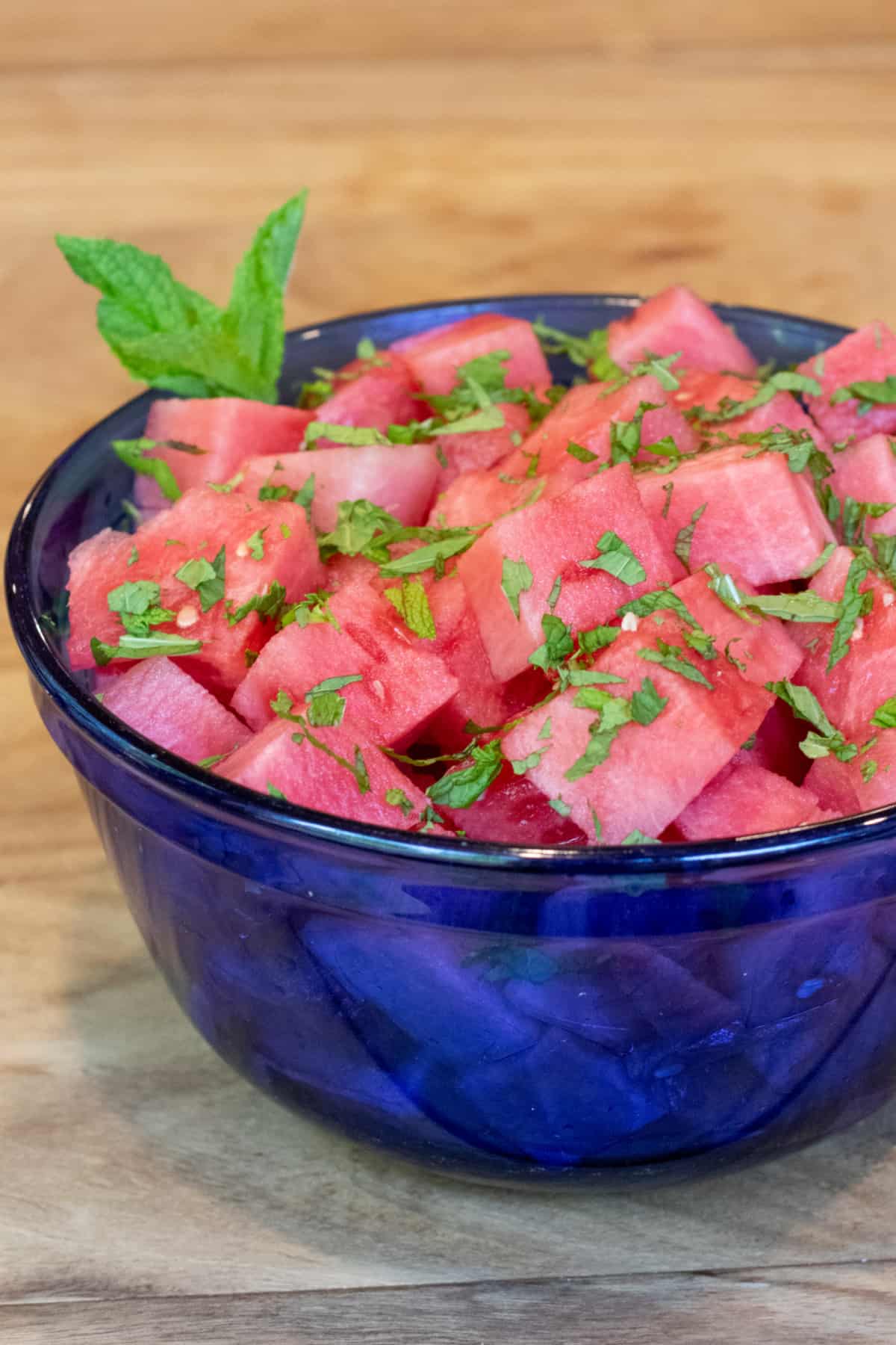 a blue bowl of cubed vodka with mint.