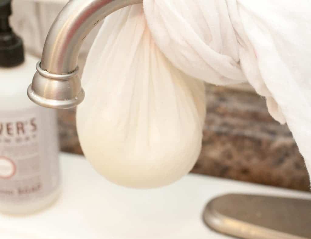 a cheese cloth with cheese draining over sink