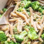 a pot of cooked penne and broccoli with a wooden spoon.