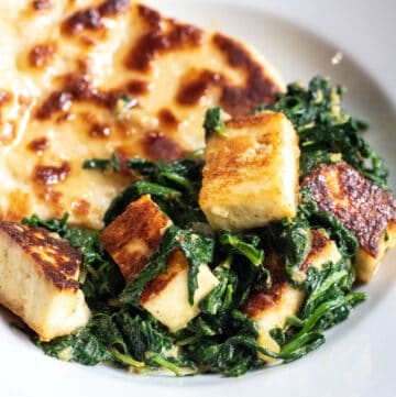 a plate with naan and paneer and spinach.