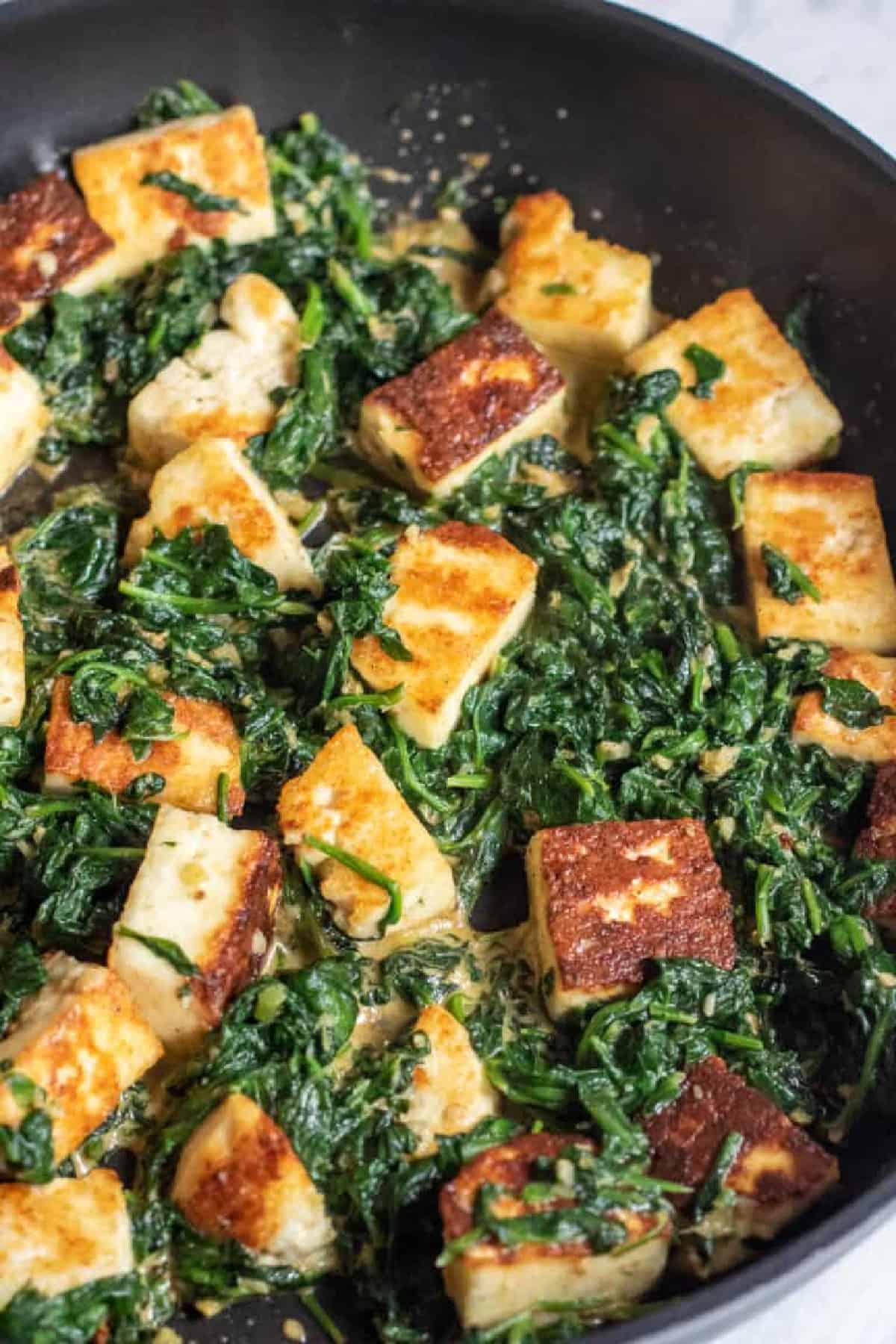 spinach in a pan with seared paneer.