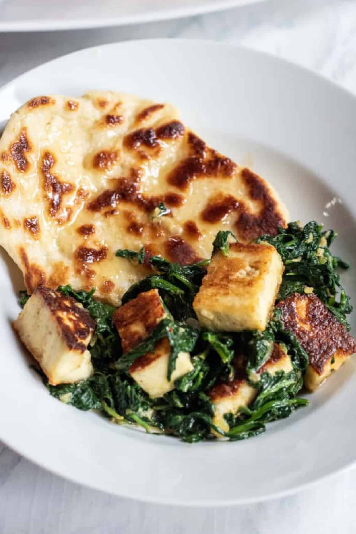 a plate with naan and paneer and spinach with Pinterest pin text.