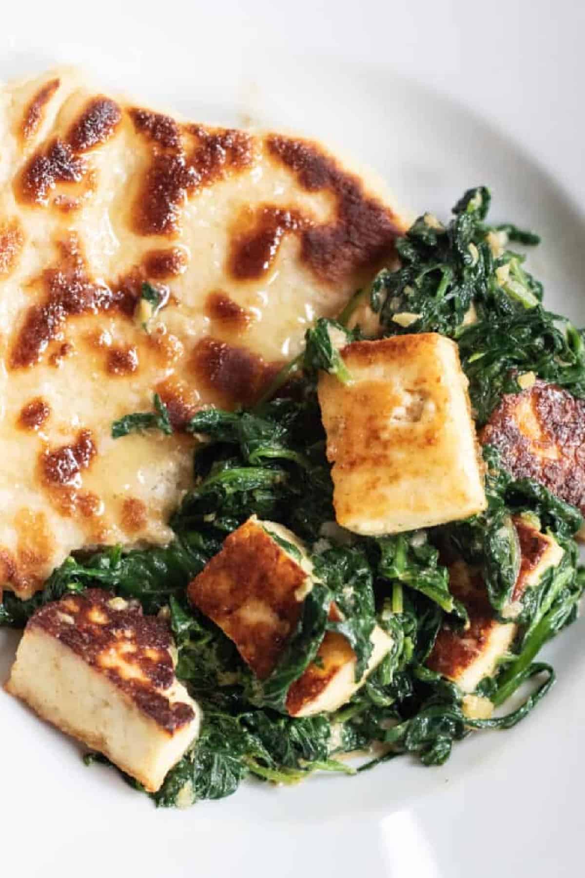 a plate with naan and paneer and spinach with Pinterest pin text.