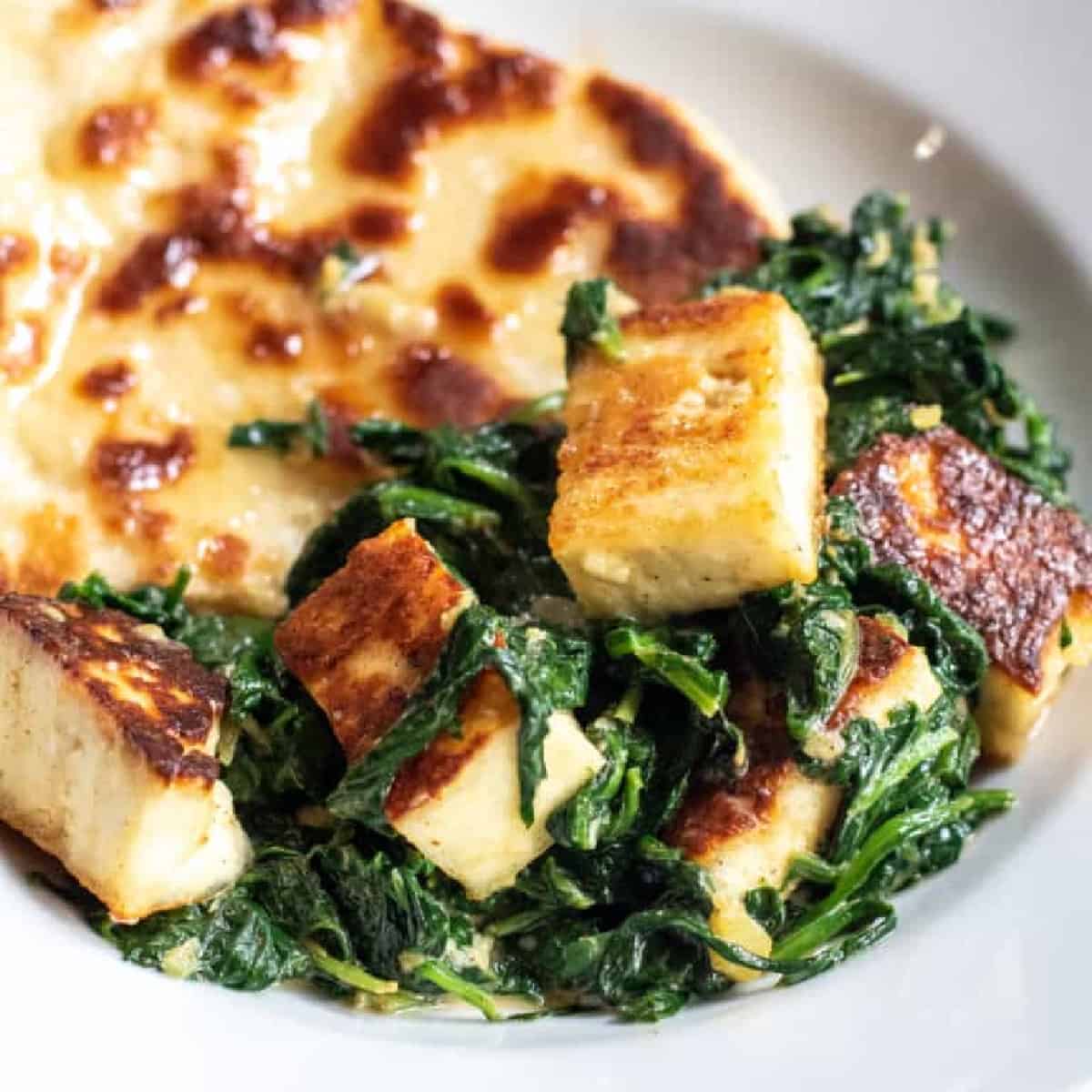 a plate with naan and paneer and spinach with Pinterest pin text.