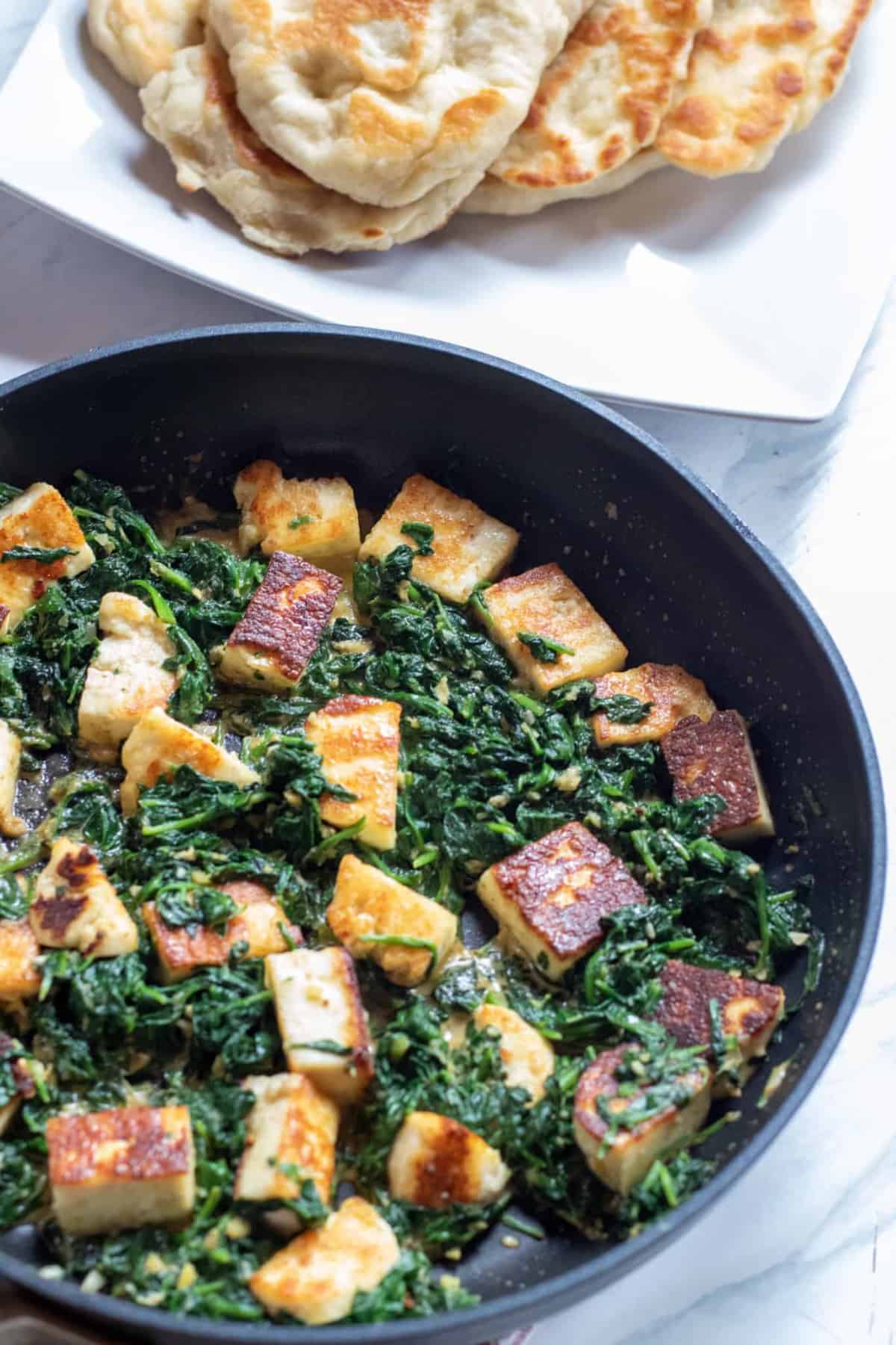 spinach in a pan with seared paneer..