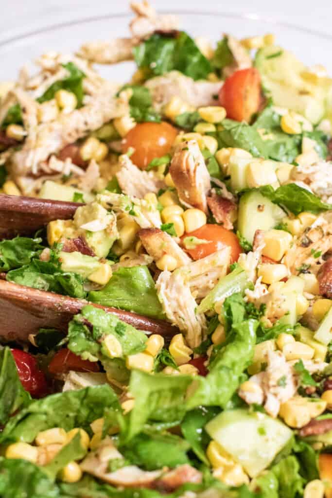 close up of a bowl of chicken avocado salad with tongs in it