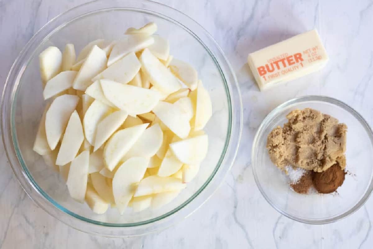 a bowl of apples, butter, and sugar and spices in a bowl.