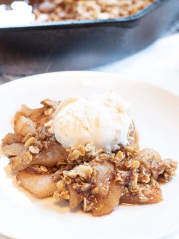 a plate of apple crisp with ice cream on top.