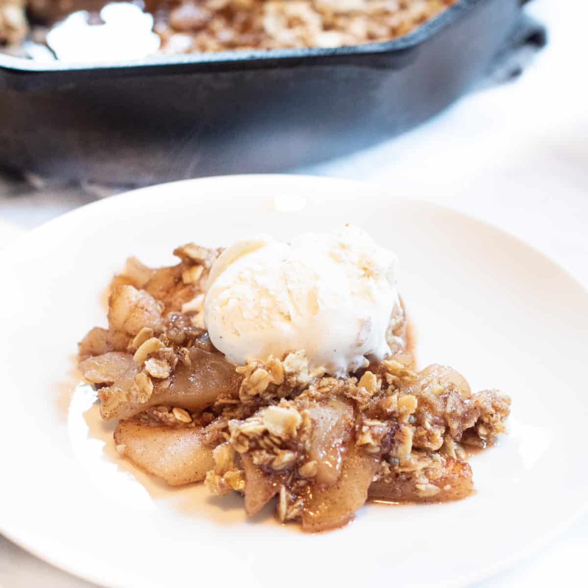 a plate of apple crisp with ice cream on top.