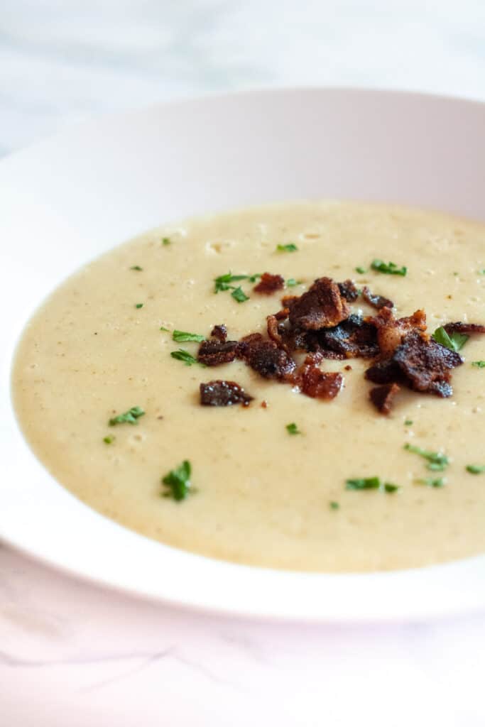 a bowl of soup with crumbled bacon and pasley