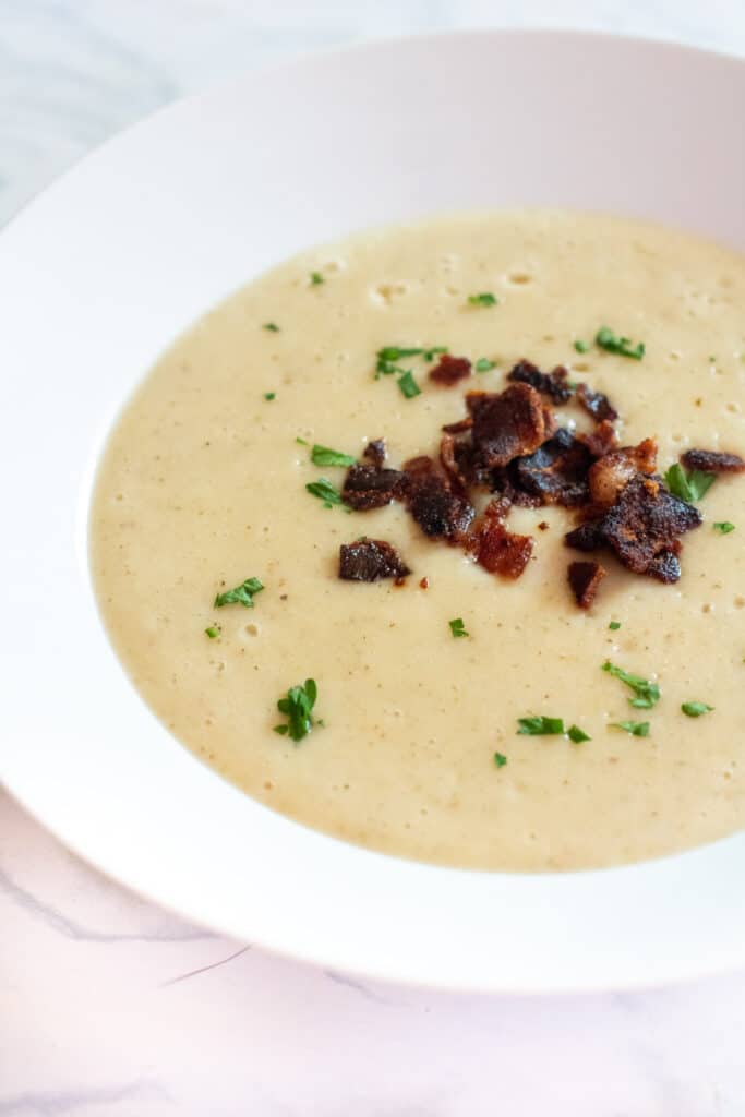 a bowl of soup with crumbled bacon and pasley