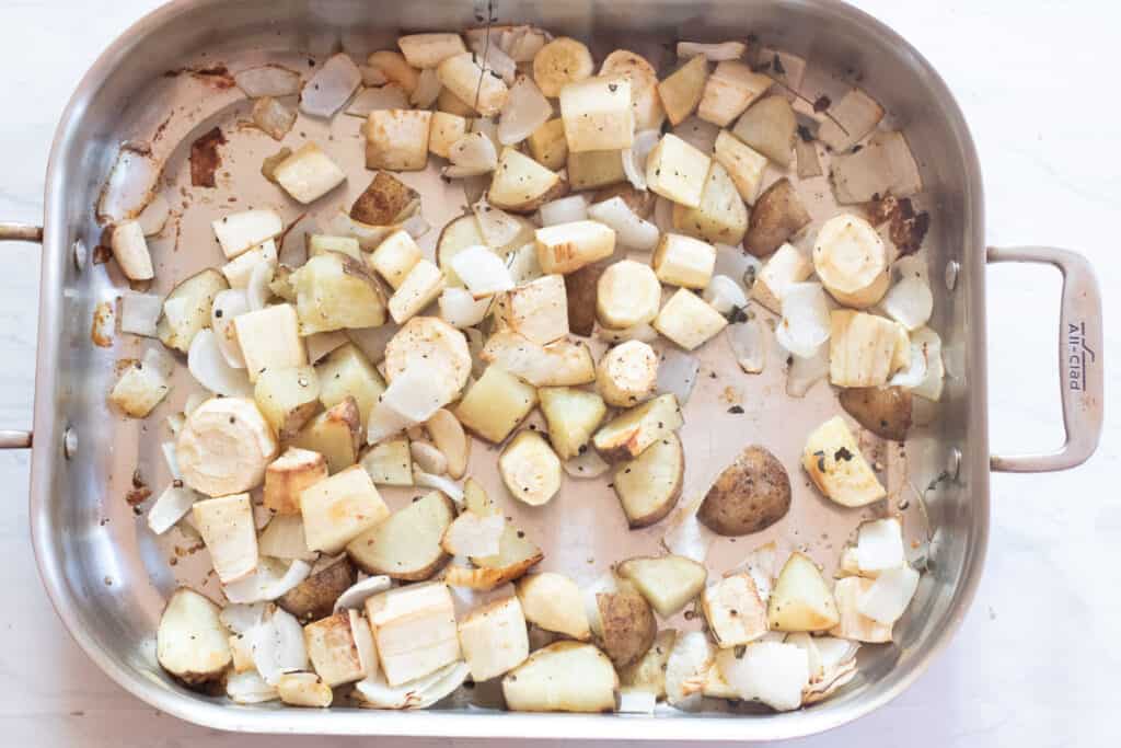 a pan with roasted potatoes, onion, and parsnips