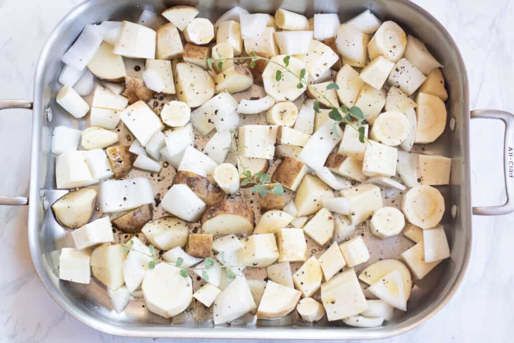 a pan with raw potatoes, onions, and parsnip