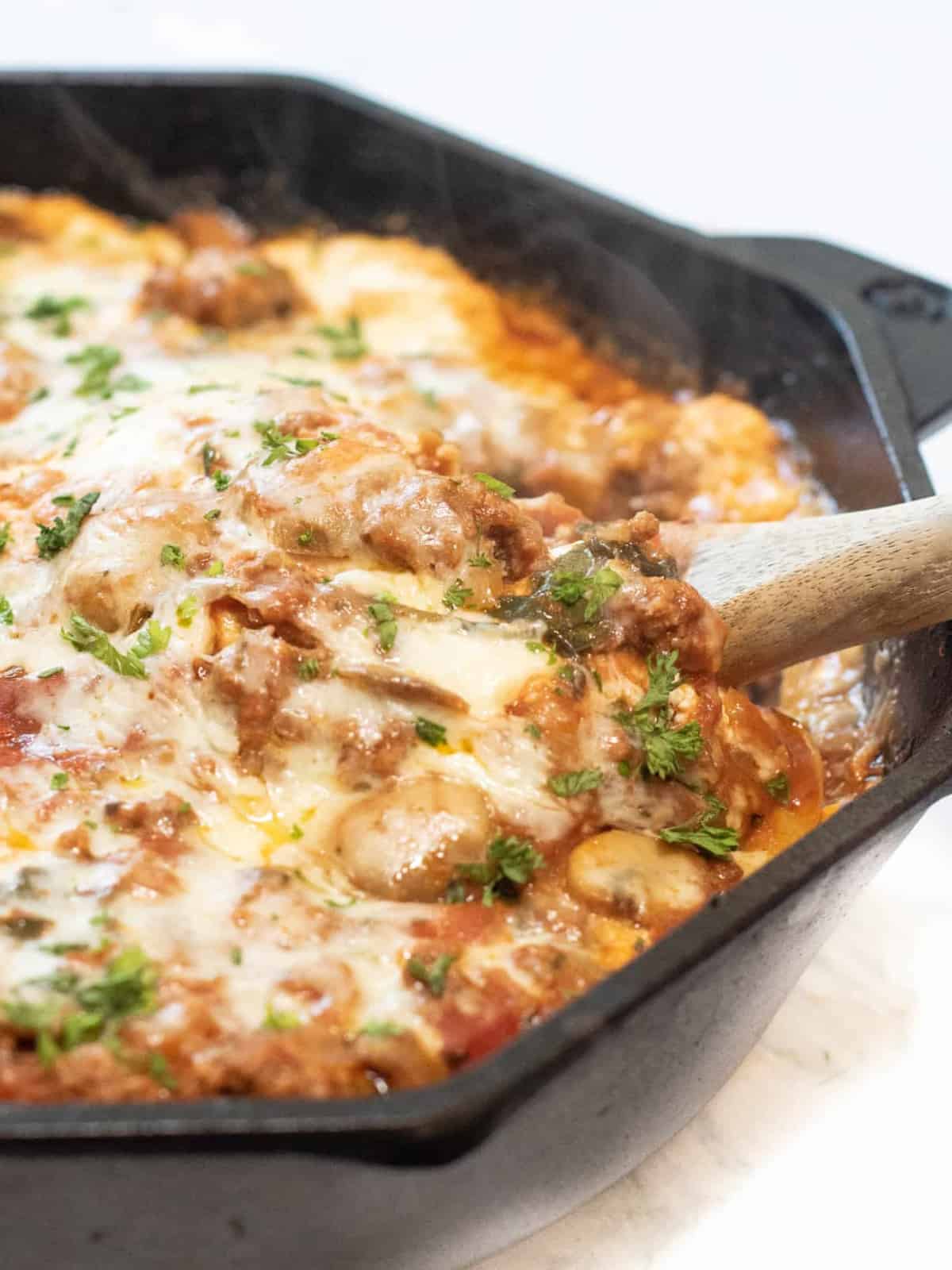 a cast iron lasagna with spoon in it.