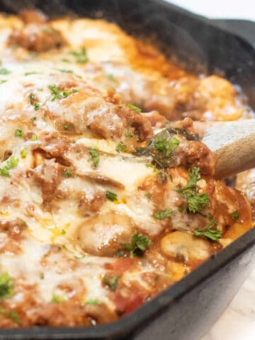 a cast iron lasagna with spoon in it.