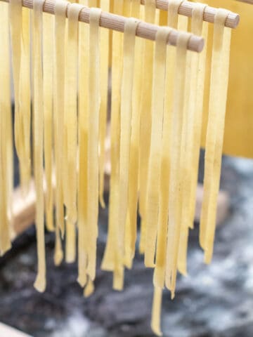 linguine pasta drying on a hanging rack.