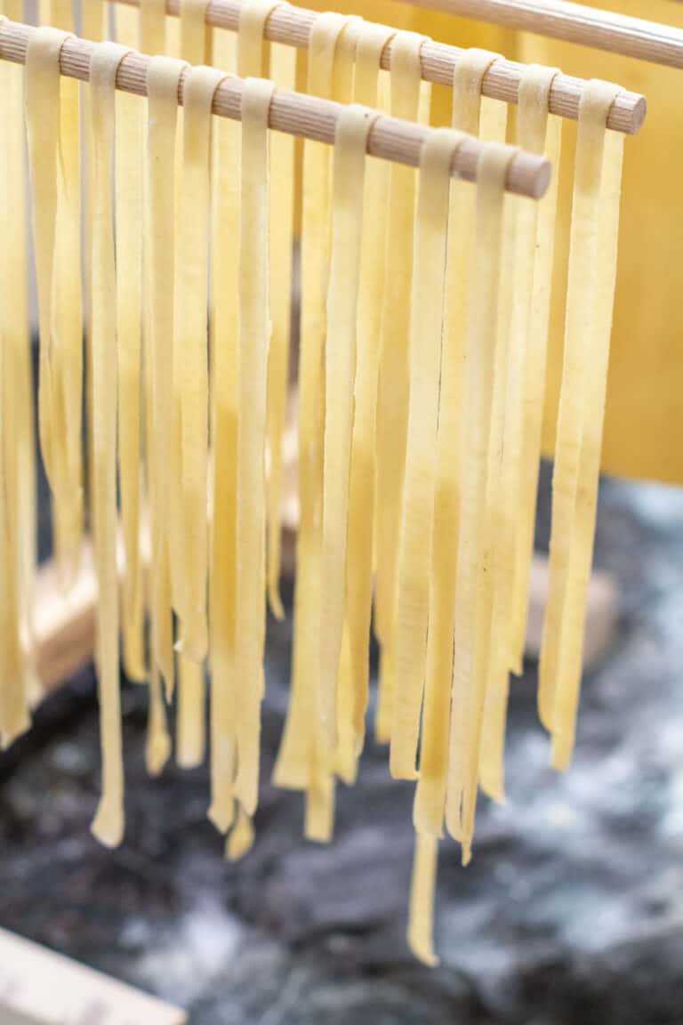 linguine pasta drying on a hanging rack.