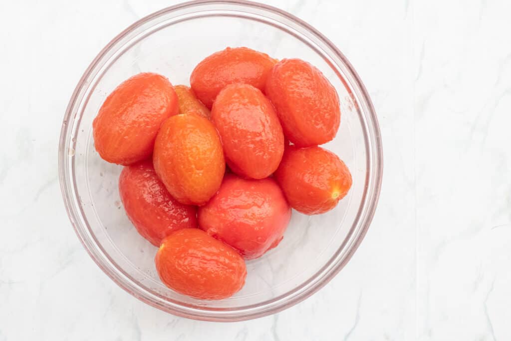 a bowl of skinned cooked tomatoes