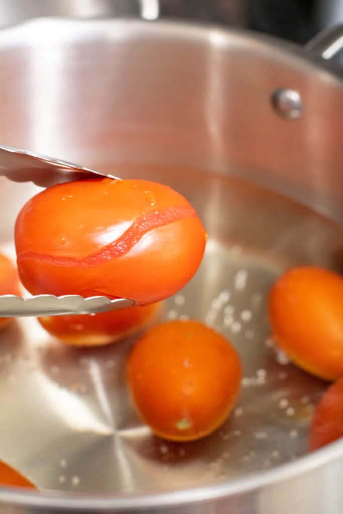 tongs holding up a tomato with split skin