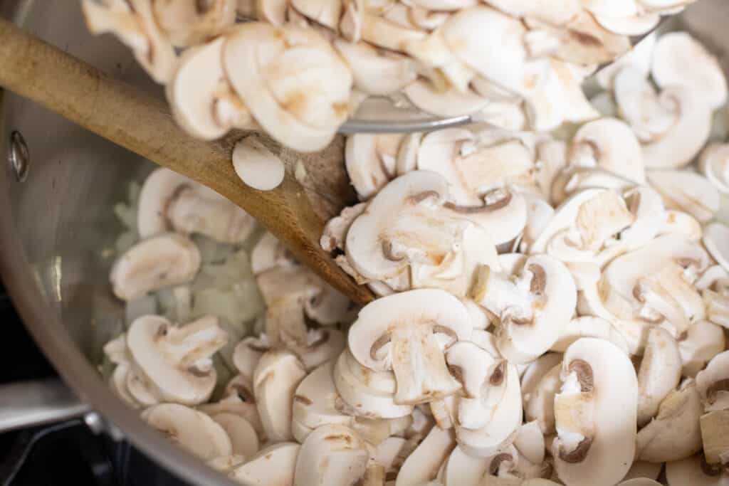 fresh mushrooms being poured in a pot 