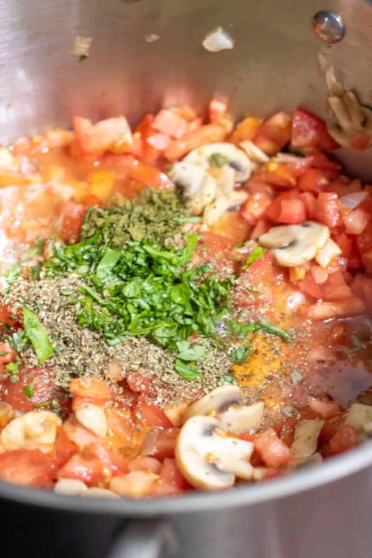 mushrooms, diced tomatoes in a pot with herbs.