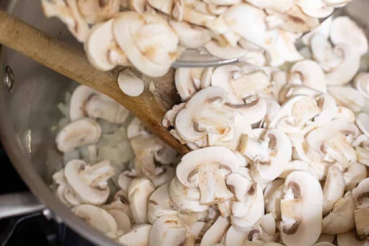 a pot of sliced raw mushrooms with a spoon.